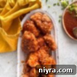 Close up of crispy Honey chicken on a white serving platter.