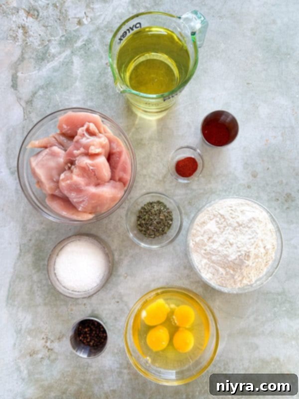 Raw chicken breasts, flour, spices, and eggs laid out, ready for the breading process of honey fried chicken.