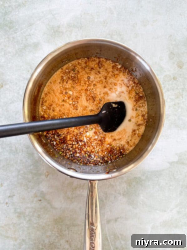 Cornstarch slurry being added to the simmering honey, garlic, and soy sauce mixture to thicken it.
