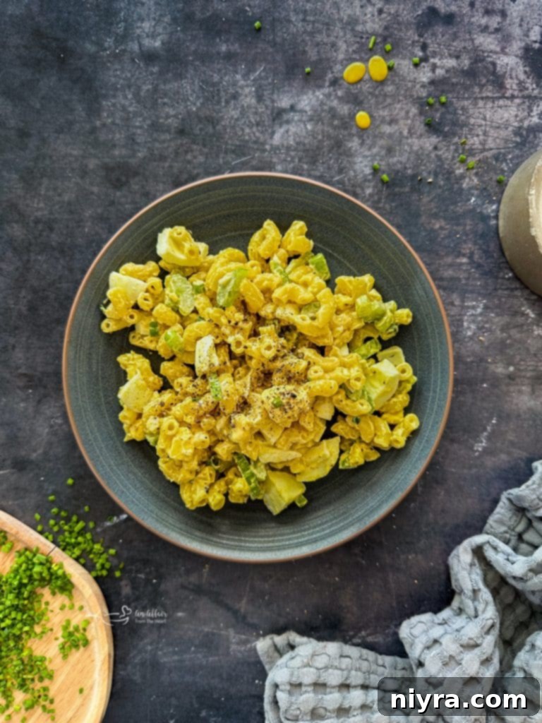 Assorted ingredients for macaroni salad, including pasta, vegetables, and dressing components, laid out on a table.