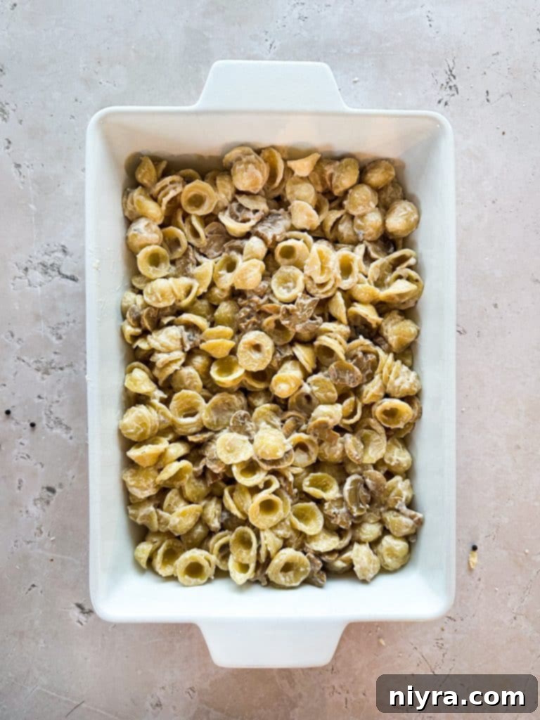 Pouring the Tuna Tetrazzini Casserole mixture into a baking dish.