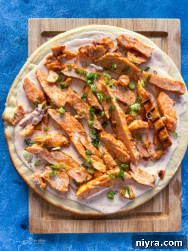 Assembling buffalo chicken pizza: sauce, chicken, onions, and cheese on crust