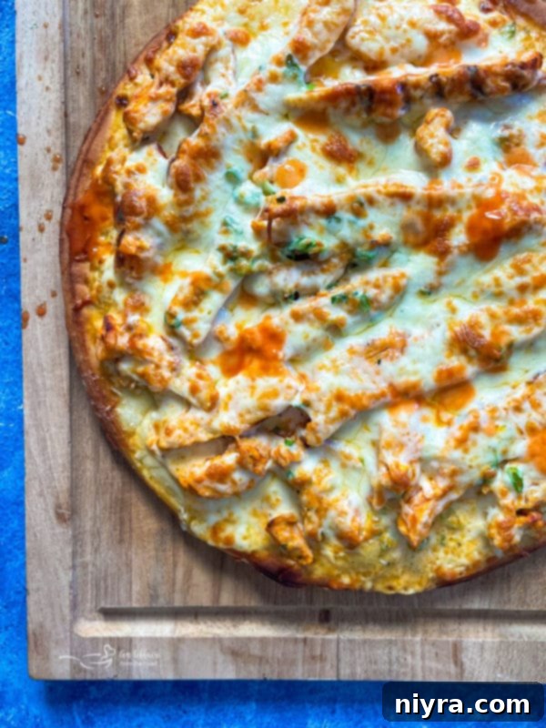 Closeup of shredded mozzarella cheese on buffalo chicken pizza before baking