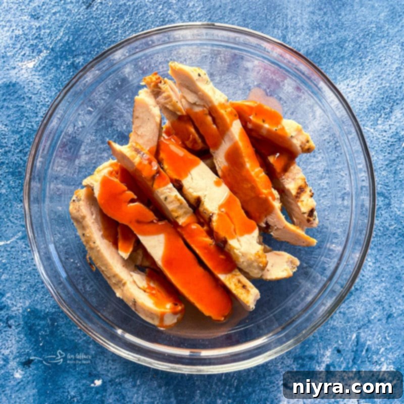 Tossing cooked chicken pieces in buffalo sauce