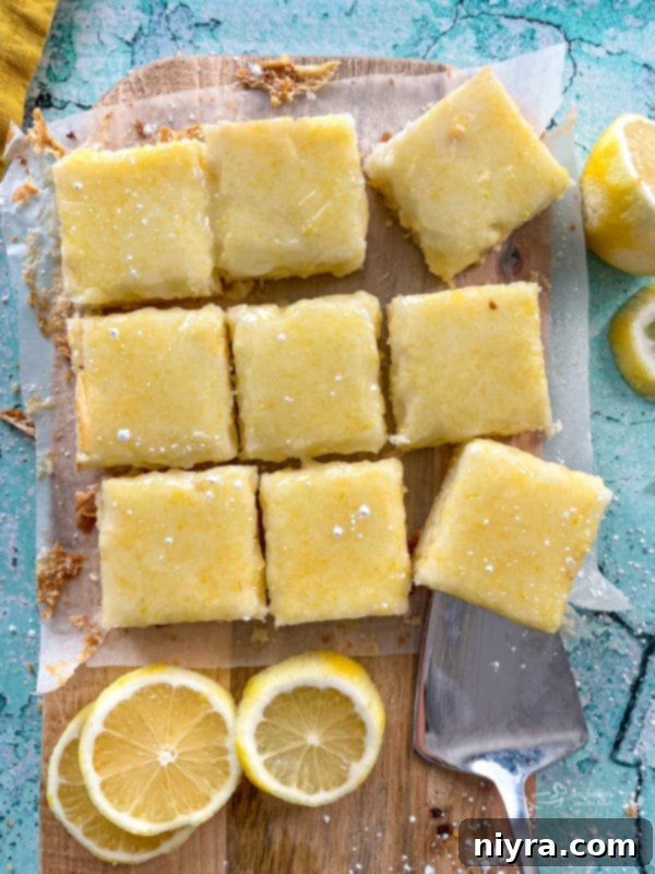 Top view of freshly baked lemon brownies on a cutting board, surrounded by fresh lemons