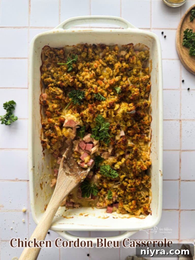 Ham and Swiss Chicken Bake 12 A wide shot of a baked Chicken Cordon Bleu Casserole in a blue casserole dish with a serving spoon.
