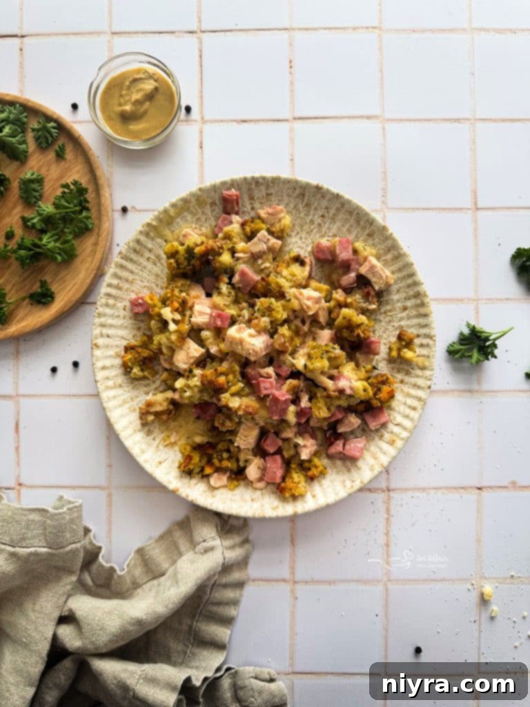 Ham and Swiss Chicken Bake 3 A close-up of a serving of Chicken Cordon Bleu Casserole on a white plate, showing the layers of chicken, ham, cheese, and stuffing.