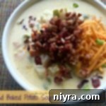 Close up of a spoonful of Loaded Baked Potato Soup, showing its creamy texture and rich toppings.