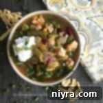 Robust Five Bean Chicken Chili 2 Overhead shot of a bowl of Five Bean Chicken Chili, garnished with sour cream and cilantro.