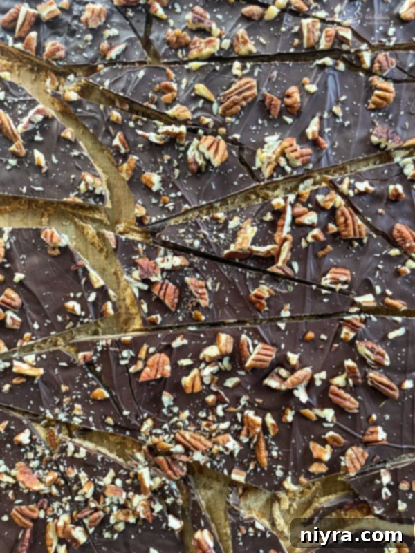 Close-up of broken pieces of graham cracker toffee brittle with pecans and chocolate, arranged for serving.