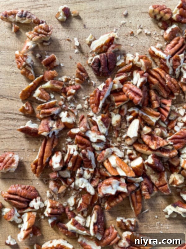 Close-up shot of chopped pecans on a rustic wooden surface, highlighting their texture.