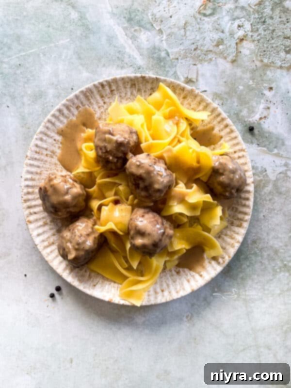 Classic Swedish Meatballs served over egg noodles with fresh parsley garnish.