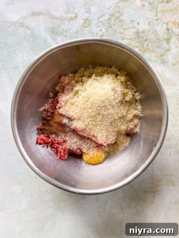 Step 2: Mixing ground meats, panko, egg yolks, and spices in a bowl.