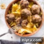 Swedish meatballs and egg noodles in a wooden bowl, up close