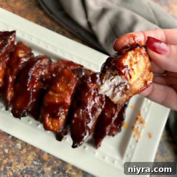 Close up of a Slow Cooker Dr. Pepper BBQ Rib with a bite out of it, showing its tenderness.