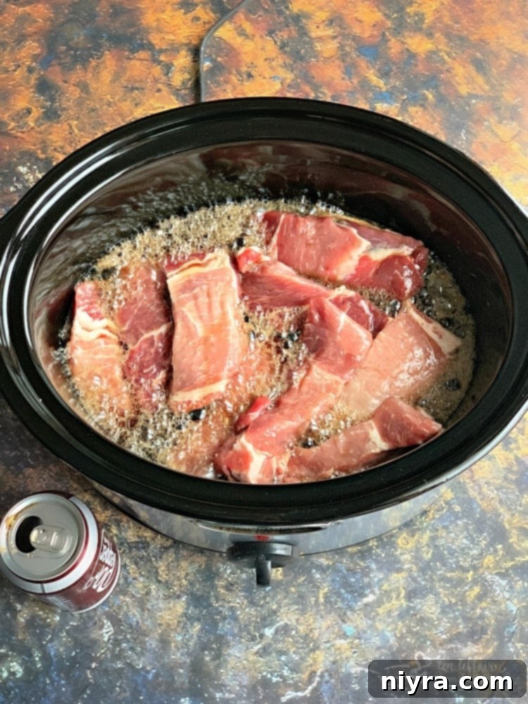 Slow Cooker Dr. Pepper BBQ Ribs cooking in a slow cooker with the lid on.