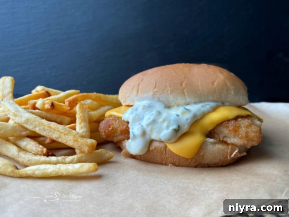 Close up view of a homemade fish sandwich and a side of french fries.