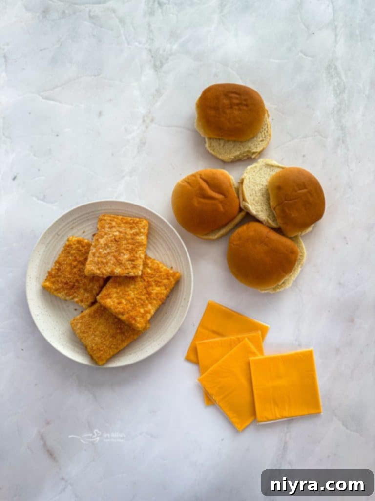 A breaded fish patty, hamburger bun, and slice of American cheese, ready for assembly.