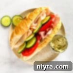 Garden Club Hoagie Sandwich and pickles on a tan plate.