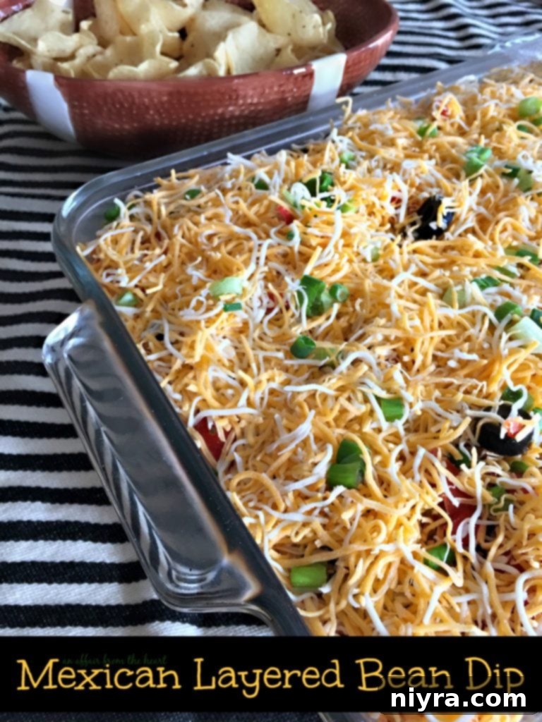 Close-up of a vibrant Mexican Layered Bean Dip, ready for serving with tortilla chips.