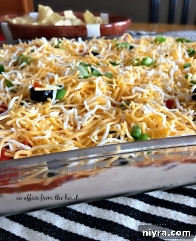 Full view of the prepared Mexican Layered Bean Dip, garnished with fresh toppings.