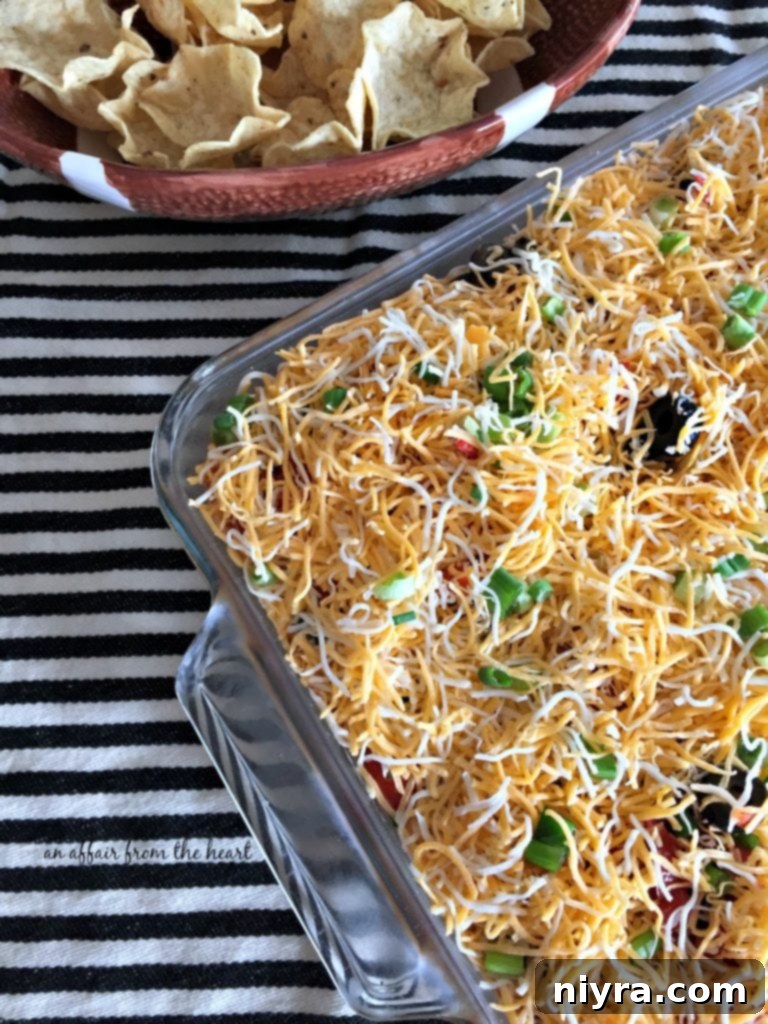 A generous pan of Mexican Layered Bean Dip ready to be devoured at a party.