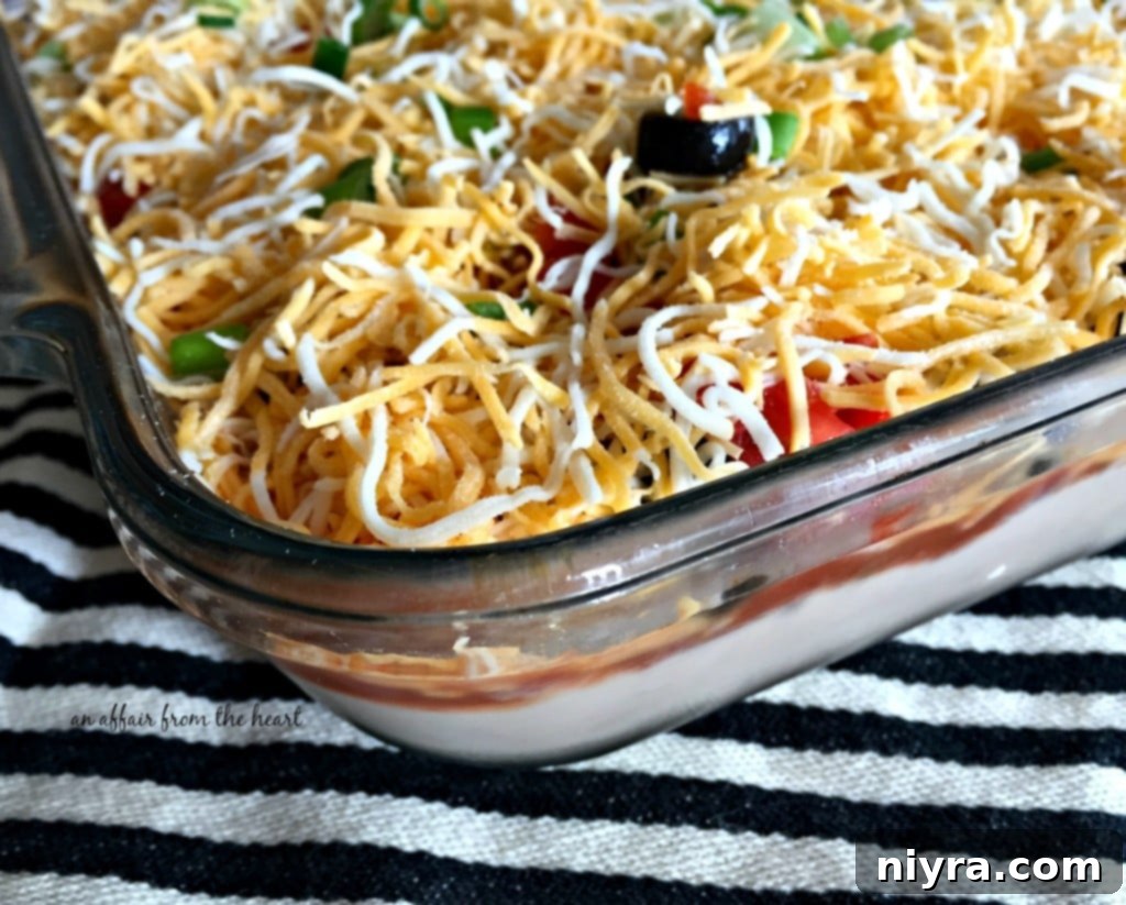 Detailed shot of the Mexican Layered Bean Dip, showcasing the fresh toppings and cheesy goodness.