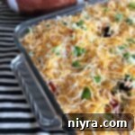 Overhead shot of the completed Mexican Layered Bean Dip in a bowl with a serving spoon.