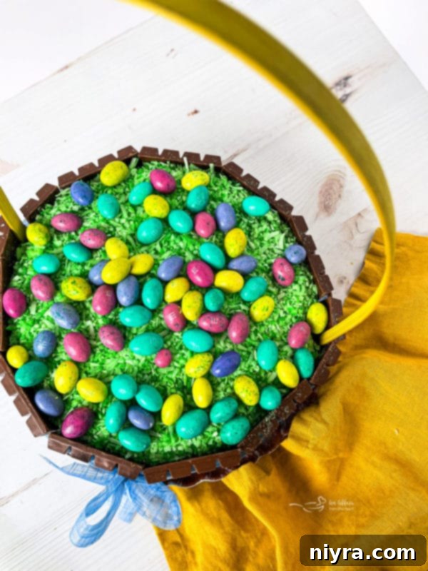 The finished Kit Kat Easter Basket Cake topped with colorful M&M Easter eggs and an elegant handle.