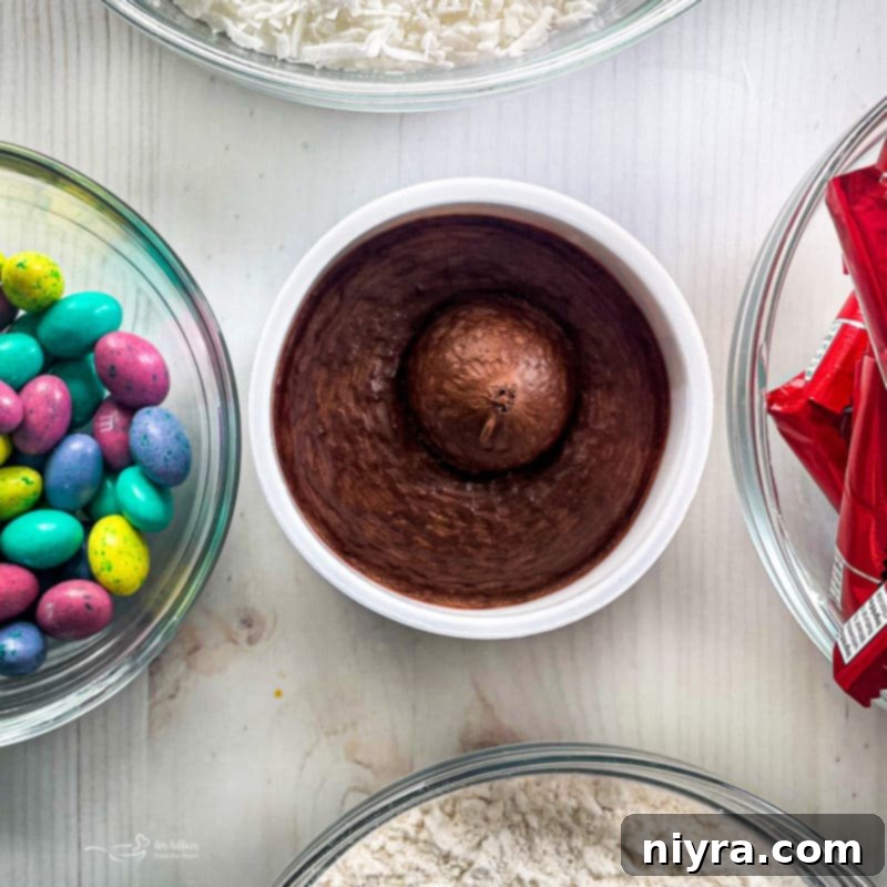 A deconstructed Kit Kat Cake showing layers of yellow cake and generous chocolate frosting before Kit Kats are applied.