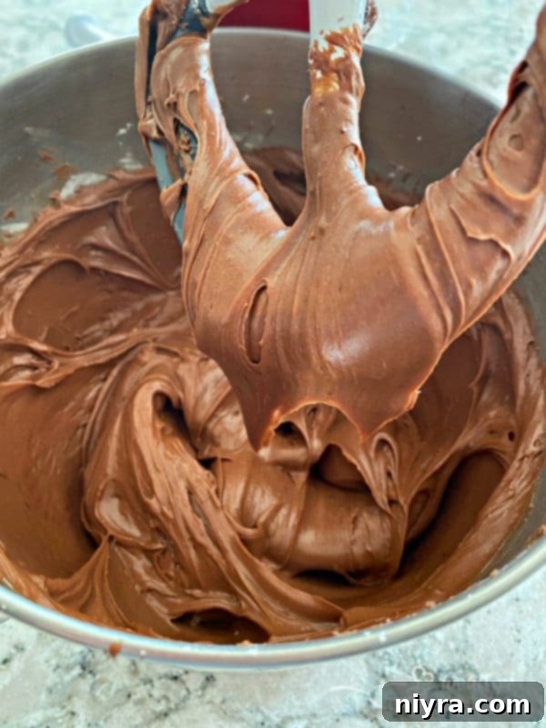 Mixing chocolate frosting with a hand mixer in a bowl