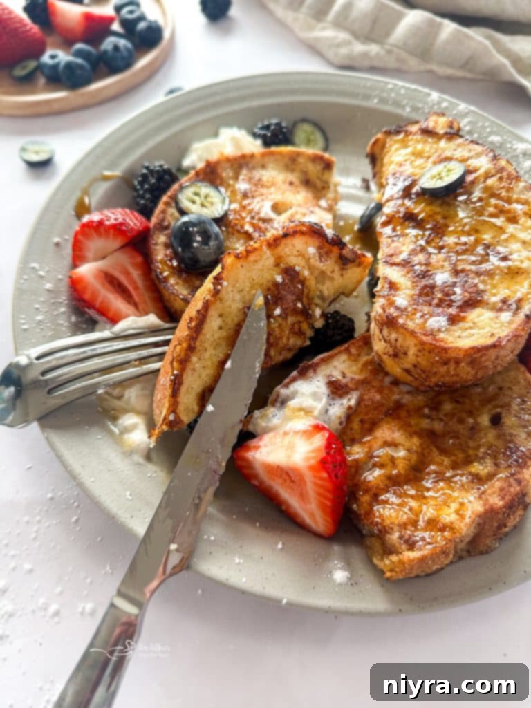 Close-up of golden French toast stack with berries and powdered sugar, inviting and delicious.