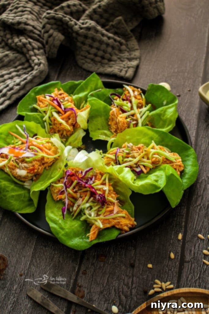 Crisp Buffalo Chicken Lettuce Wraps 3 Two Buffalo Chicken Lettuce Wraps on a white plate, garnished with fresh toppings