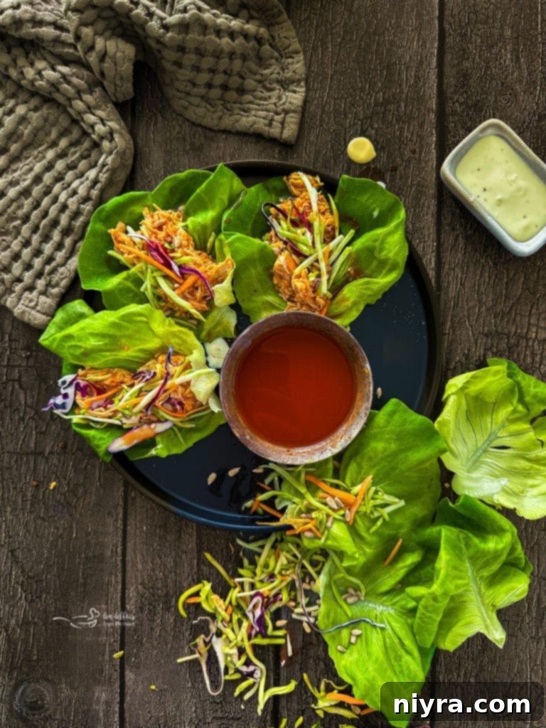 Crisp Buffalo Chicken Lettuce Wraps 4 Three Buffalo Chicken Lettuce Wraps displayed on a wooden board