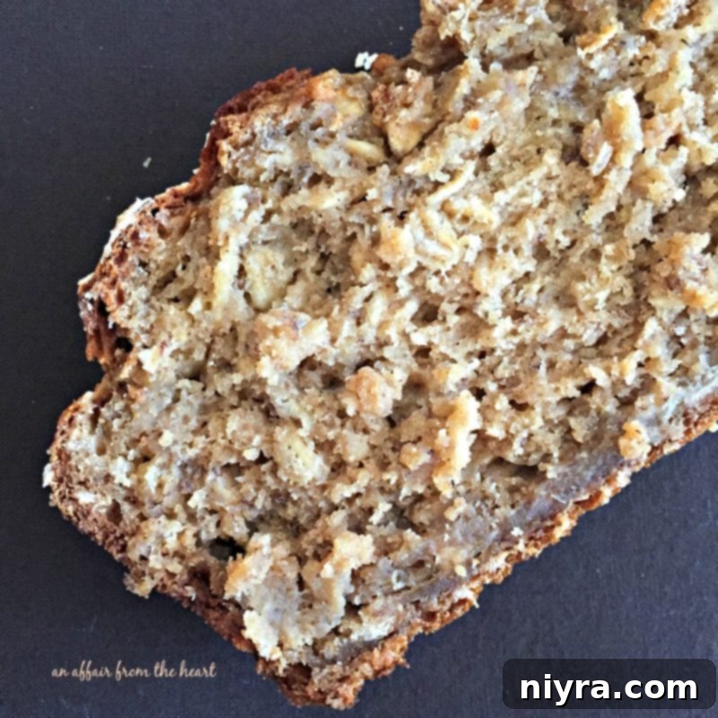 A cross-section of Banana Applesauce Oatmeal Bread revealing its moist, tender crumb with specks of oats and banana.