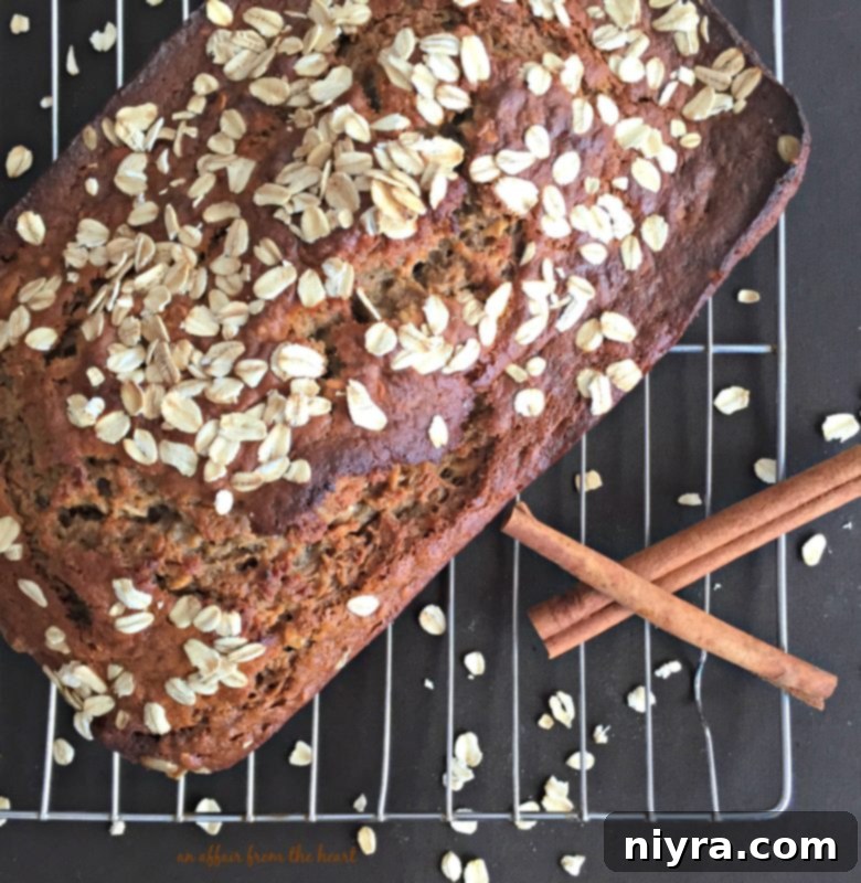 An overhead shot of a freshly baked Banana Applesauce Oatmeal Bread loaf in a pan, topped with oats.