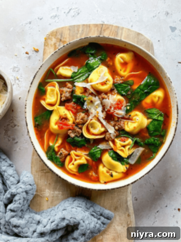 Tortellini soup in a white bowl, garnished with fresh herbs, a hearty and easy meal option