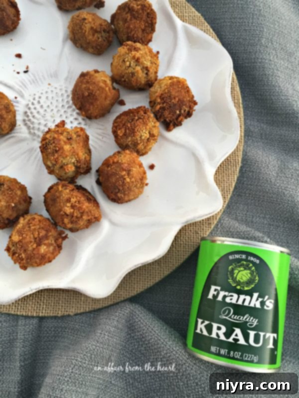 Several Sauerkraut Balls artfully arranged on a white plate with a side of dipping sauce and fresh herbs.