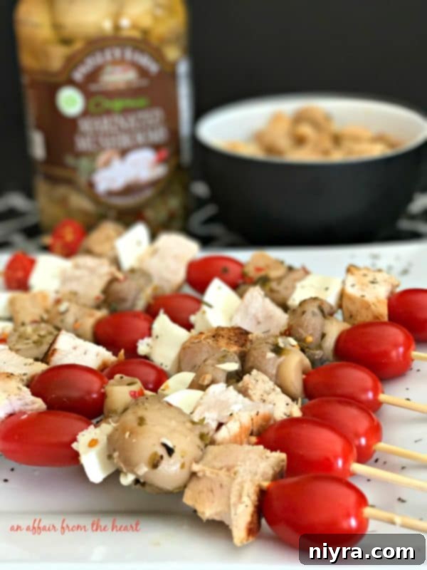 Hand reaching for an Italian Chicken and Mushroom Appetizer Skewer, showcasing its delicious appeal.
