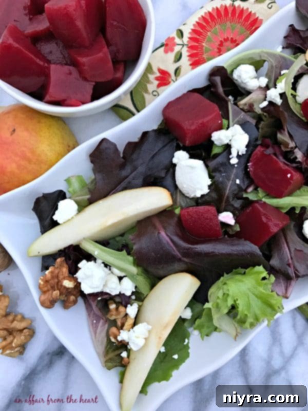 Close-up of a vibrant pickled beet salad featuring fresh spring greens, ruby red beets, crisp pears, crunchy walnuts, and creamy goat cheese