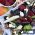 Overhead shot of a vibrant Pickled Beet Salad with Pears, Walnuts & Goat Cheese on a white platter