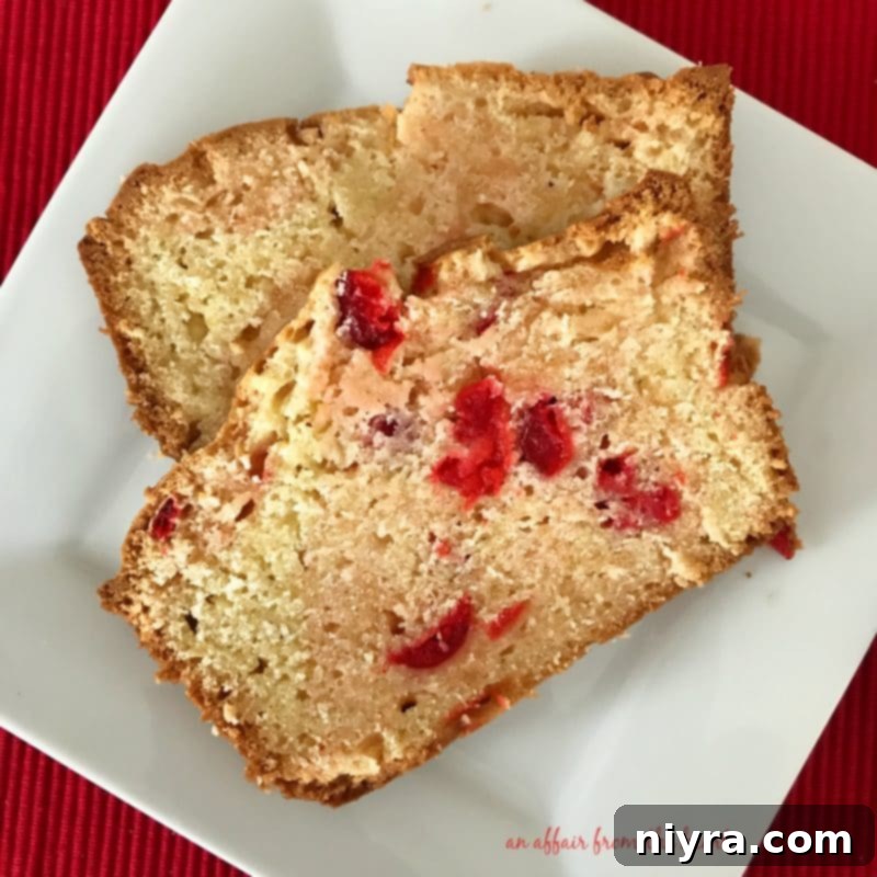 A beautifully presented slice of homemade Cherry Cheese Bread on a white plate, highlighting its moist texture and juicy cherry pieces.