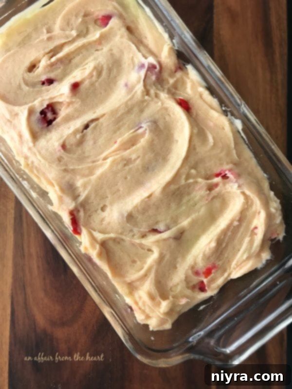 A selection of fresh ingredients for Cherry Cheese Bread, including cream cheese, butter, sugar, flour, eggs, almond extract, and maraschino cherries, artfully arranged on a counter before preparation.