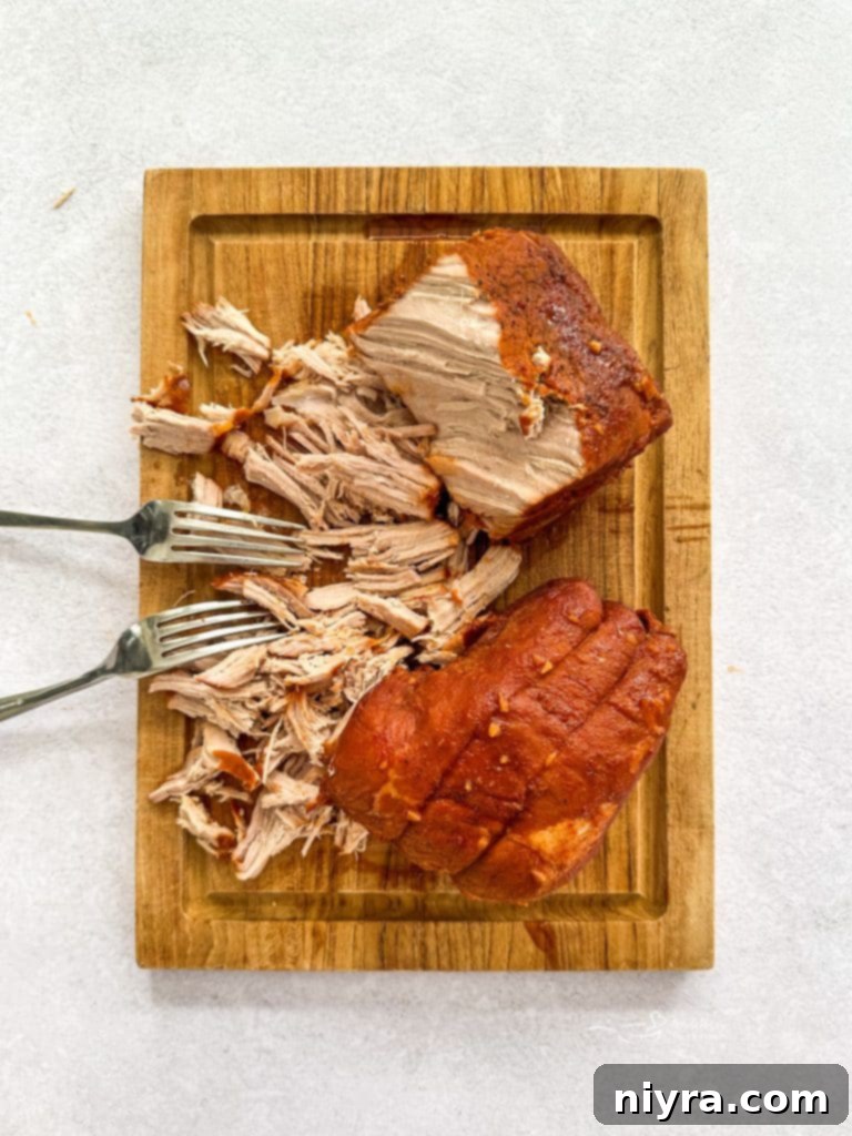 Cooked pork roast being removed from the slow cooker onto a cutting board.