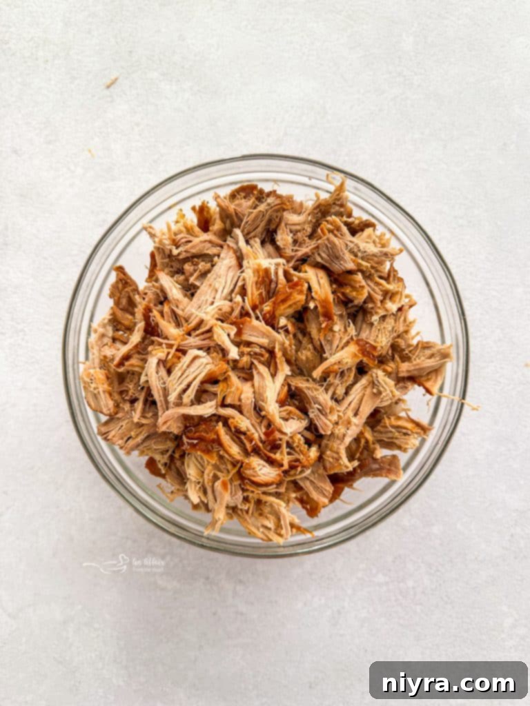 Shredded pork on a cutting board, ready to be returned to the sauce.