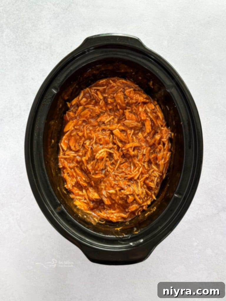 Sauce in the slow cooker thickening after cornstarch slurry has been added.