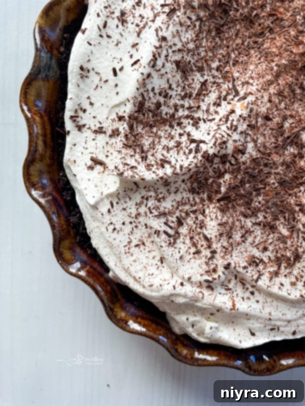 Top view of a decadent French Silk Pie, crowned with whipped cream and chocolate curls, ready to be served.