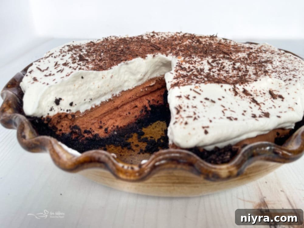A beautifully presented whole French Silk Pie, rich with chocolate and topped with whipped cream, on a pie plate.