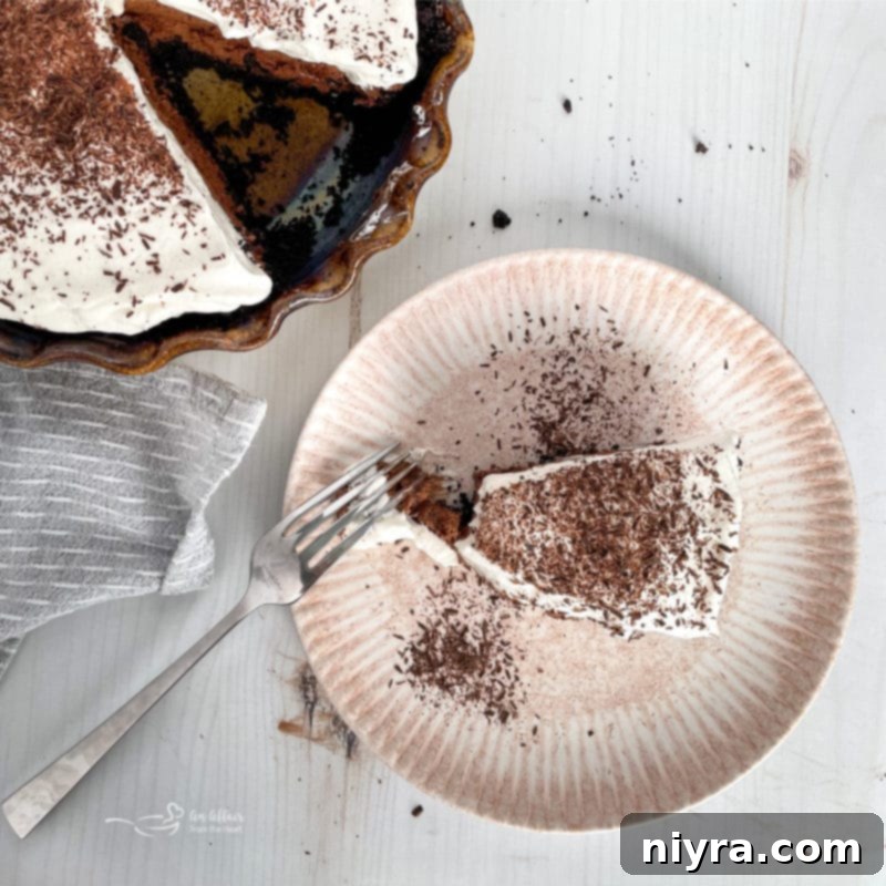 A perfect slice of French Silk Pie on a white plate, highlighting its layers and garnishes.
