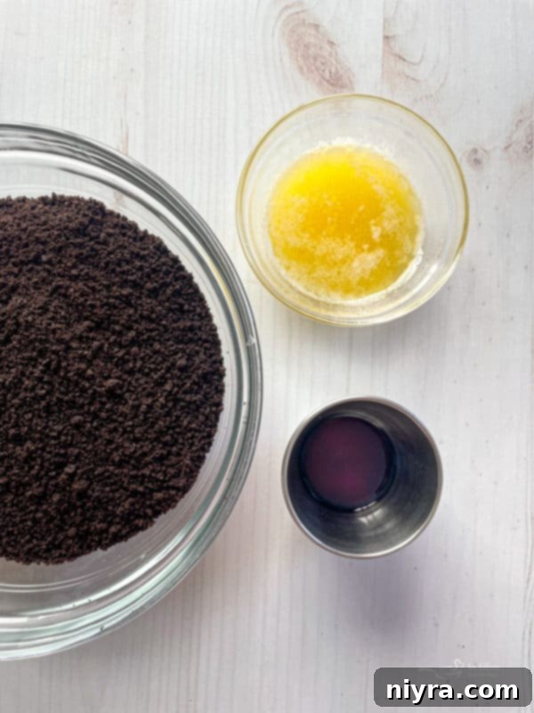 Bowls containing Oreo crumbs, softened butter, and vanilla extract, ready for the pie crust.